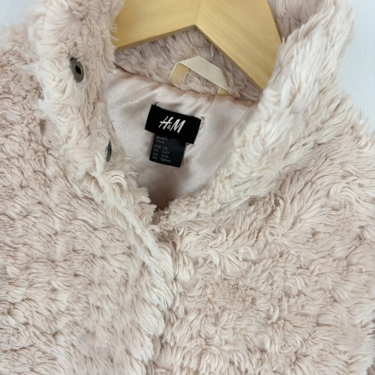 H&M címké és kattintós záródás a plüss kabáton közelebbről